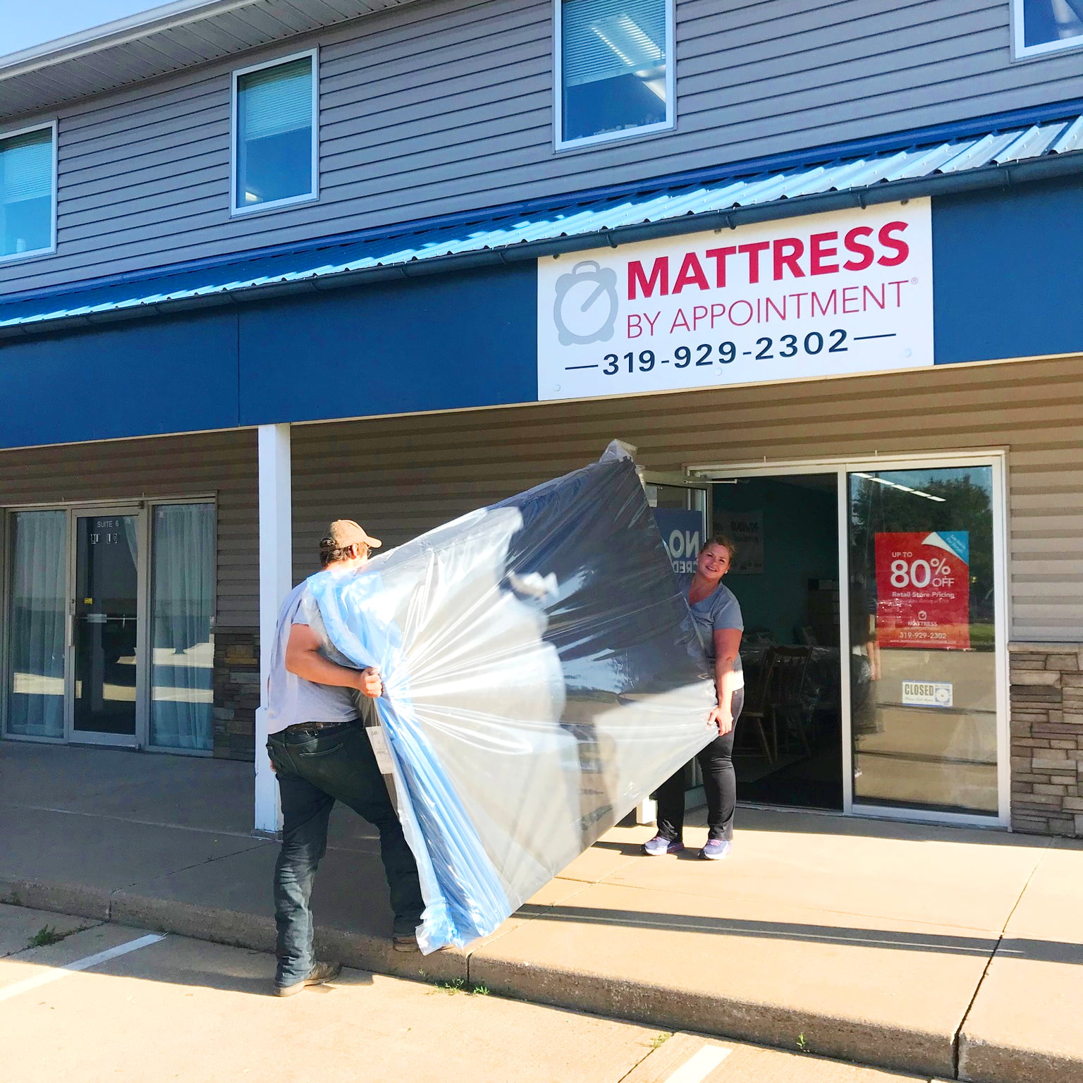 A man and a woman carrying a new mattress into Mattress by Appointment in Sheboygan, WI.